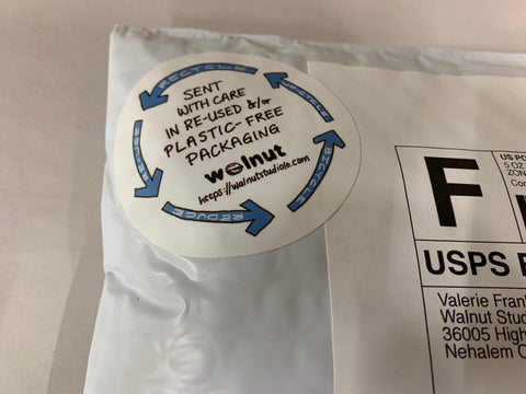 An outgoing mailer with a hand-written sticker from Walnut Studiolo on it saying this was packaged up with care using upcycled or plastic-free packaging