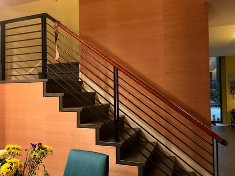 A metal stair bannister partly wrapped with vegetable-tanned leather at a customer's house