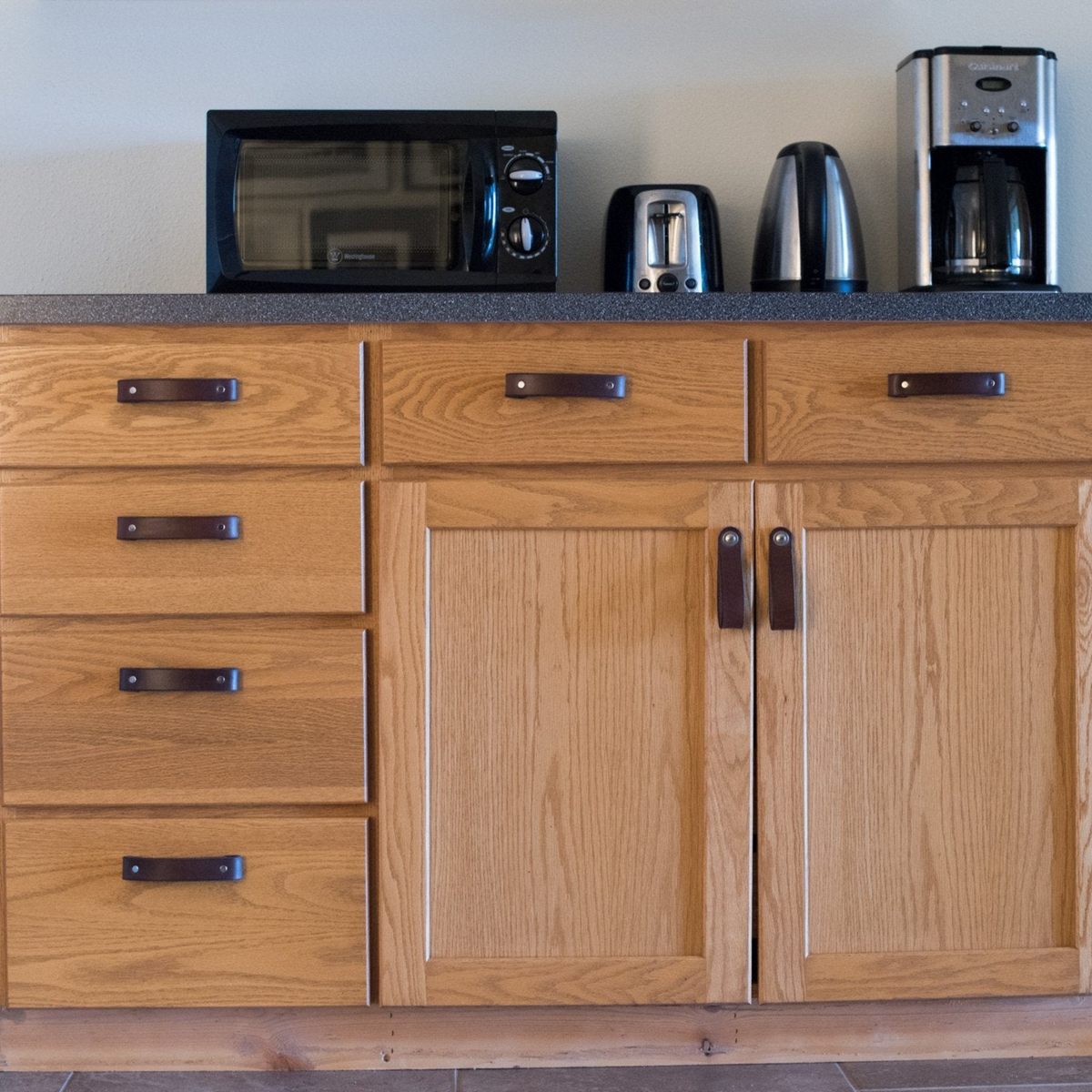 View from across the room: dark brown leather handle on an oak kitchen island cabinet 