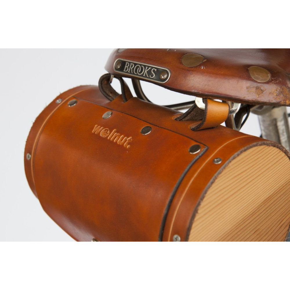 Close-up of honey leather barrel bag attached to the back of a worn Brooks bike seat