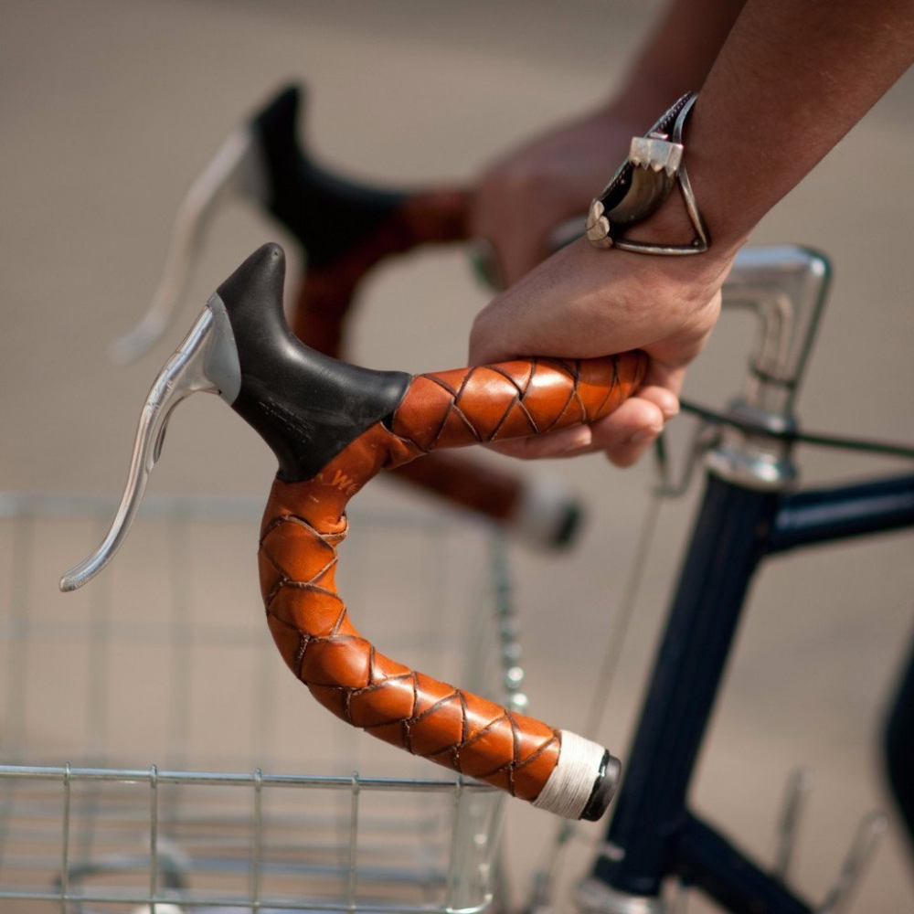 Black bicycle rider with hands on handlebars wrapped in honey colored braided leather