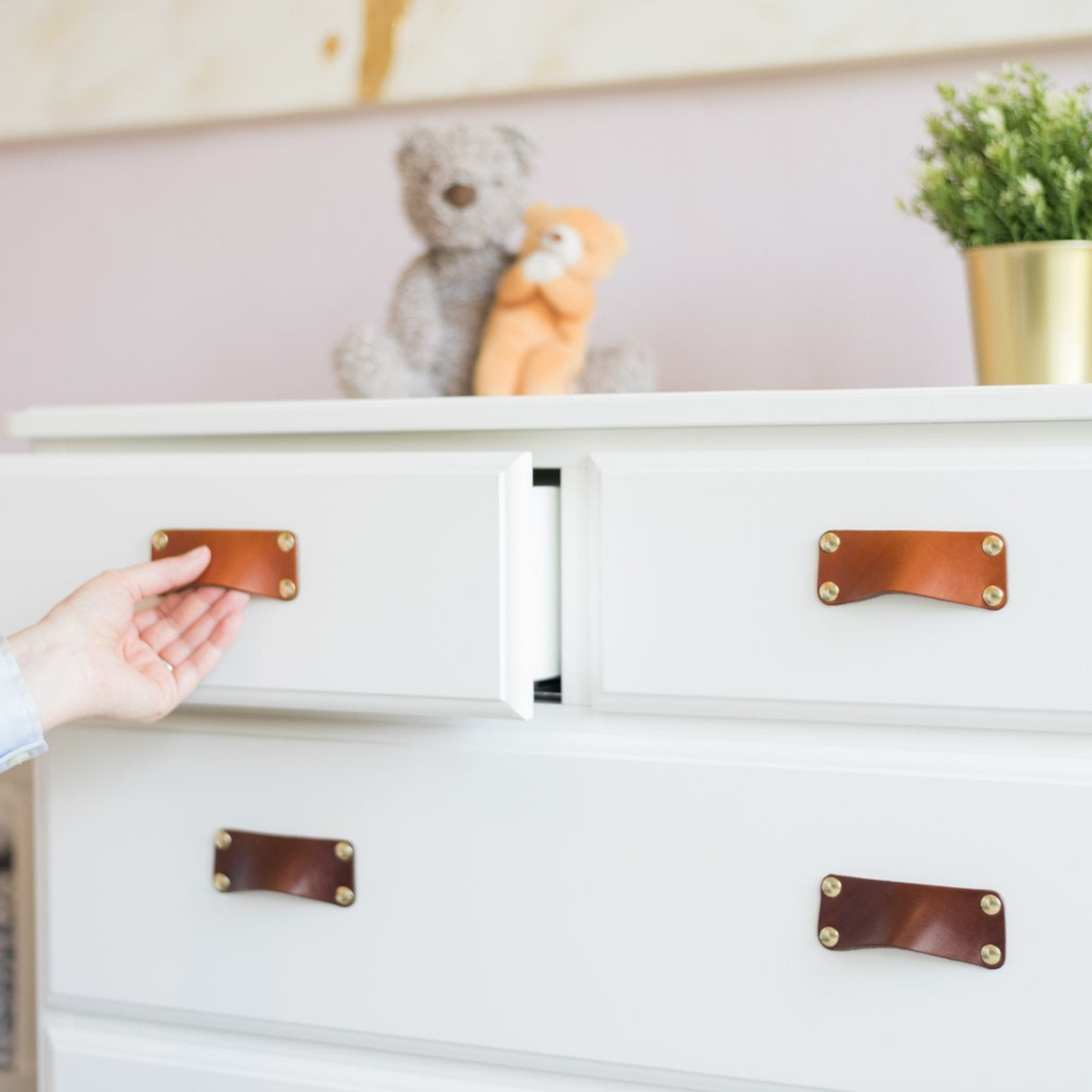 White IKEA HAUGA Chest of Drawers with the Walnut Leather Bin Pull installed in three different colors like an ombre rainbow, growing darker towards the floor.