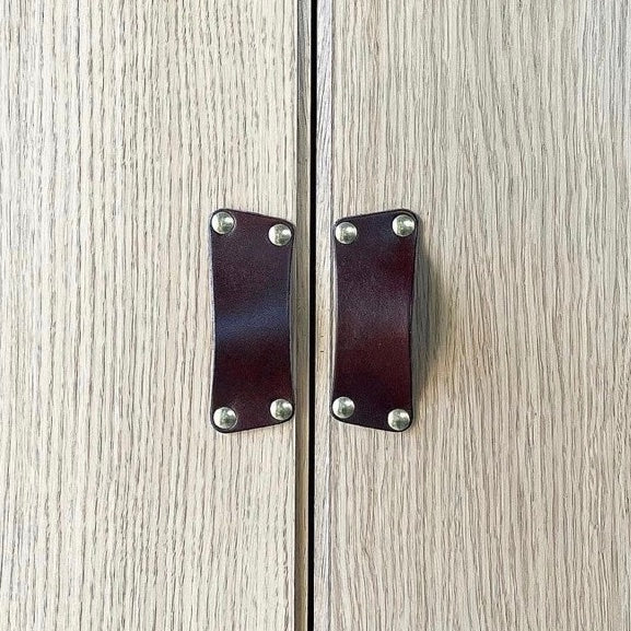 Customer photo showing beachy driftwood gray colored wood closet doors with dark brown Morrison leather bin pulls installed sideways where the two closet doors meet.