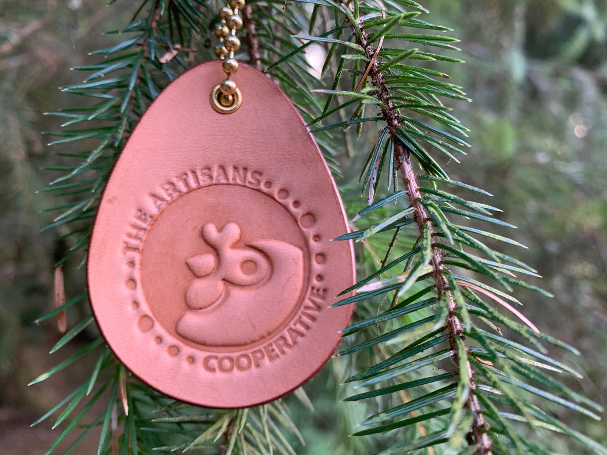 Leather fundraiser for Artisans Cooperative hung from a tree like a Christmas ornament